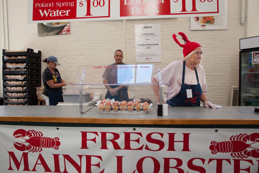 A woman selling lobster rolls in the Maine building says Maine lobster rolls are better than the Connecticut kind. Host John Dankosky disagrees. (Credit: Ryan King/WNPR)