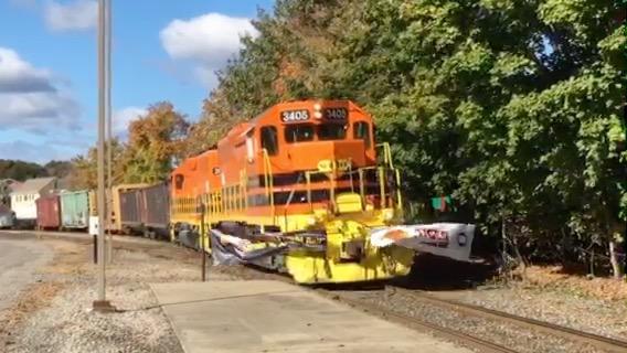 A locomotive breaks a banner across the tracks in Willimantic to mark the start of a rail upgrade project. Credit: Harriet Jones / WNPR