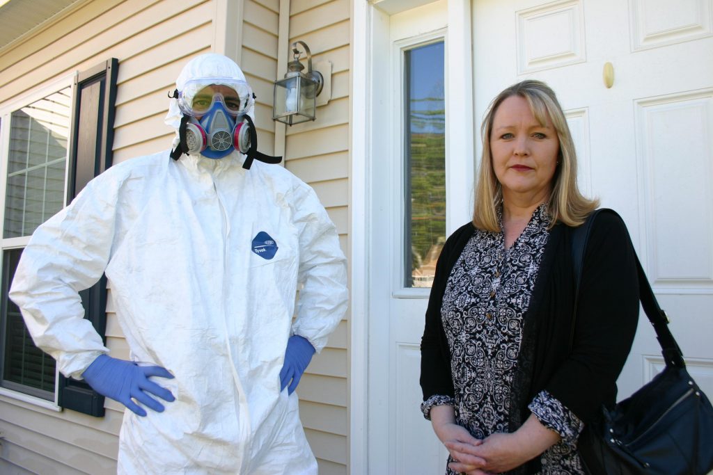 Dan and Dawn Crim stand on the front porch of the Laconia home they fled in 2014. They say shoddy construction and water infiltration led to mold and yeast, which in turn made them and their son sick. Photo credit: Jack Rodolico