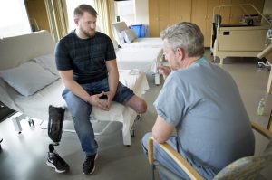 Brandon Korona, an Army veteran whose left leg was injured in an IED explosion in Afghanistan, talks with Dr. Matthew Carty at Brigham and Women’s Faulkner Hospital in Boston. Photo by Robin Lubbock for WBUR