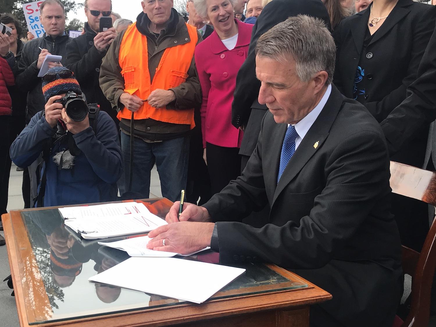 Gov. Phil Scott signs three pieces of gun control legislation amid boos and cheers on the front steps of the statehouse Wednesday, April 11, 2018. Photo by Emily Alfin Johnson for VPR.