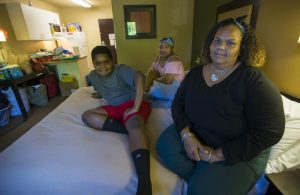 Lisbeth Sandoval, (far right), her daughter, Sheylibeth, and her son, Stephen, inside a hotel room in Lowell. Photo by Jesse Costa for WBUR