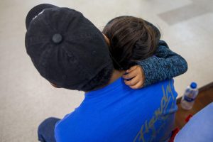 A young migrant family waits for the arrangements for their bus at Catholic Charities in McAllen, TX. Photo by Jesse Costa for WBUR