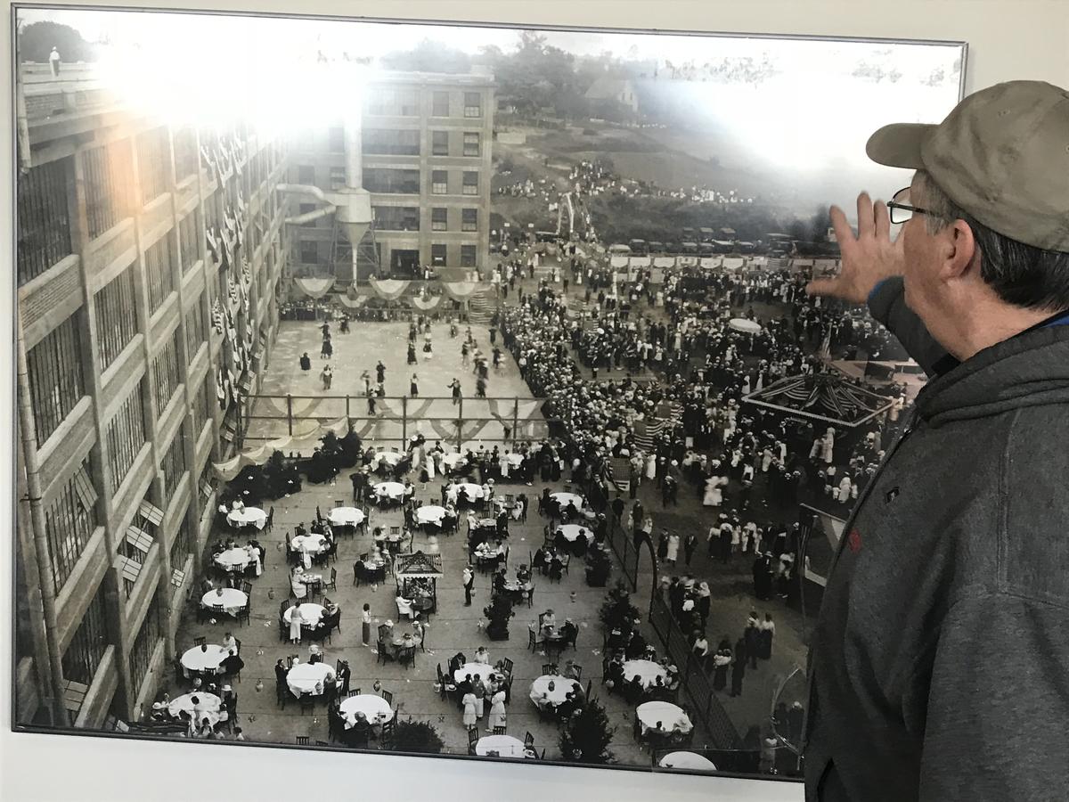 Mike Bernier points to a photo of a factory employee party that took place on the grounds of what is now the Sundial Center. Photo by Robert Garrova for NHPR