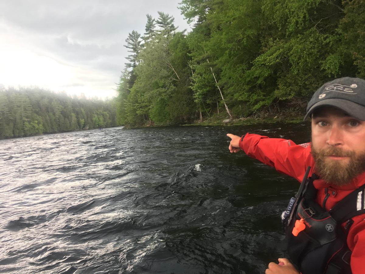 Kevin Ross, a rafting guide for Dead River Expeditions, points to a section of the Kennebec River Gorge where CMP proposes a major transmission line crossing. It would arc over an otherwise undeveloped seven mile stretch of the river. Ross opposes the plan, but CMP and other stakeholders have struck a mitigation deal that would include donations of recreational land and funding for economic development in the West Forks area. Photo by Fred Bever for Maine Public