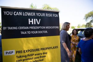 Tatiana Melendez, standing tall next to the PrEP promotional poster, is doing HIV prevention outreach at Hartford's Barnard Park on a recent Friday. Melendez, a.k.a. Lady Tatiana, began working for the Community Renewal Team in May as its PrEP navigator. Photo by Ryan Caron King for Connecticut Public Radio