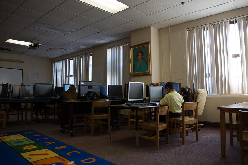 Los estudiantes del tercer grado, incluso los evacuados de Puerto Rico, trabajan en un programa de matemáticas en la biblioteca de la Escuela Primaria Sánchez en Hartford. Un retrato de la homónima de la escuela, María Colón Sánchez, examina la habitación. (Ryan Caron King/ Connecticut Public Radio)