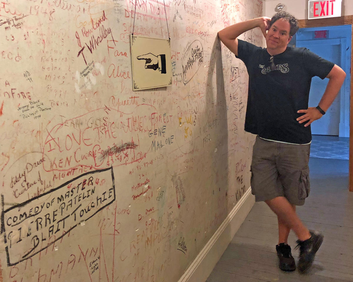 Chris Planetta, president of the Borderline Players' board of directors, stands in a hallway between backstage and the dressing rooms, where actors from productions past have signed the walls. This area, the stage and the front rows of seats are in Canada. Other audience seating, including the balcony, is in the United States. Photo by Amy Kolb Noyes for VPR