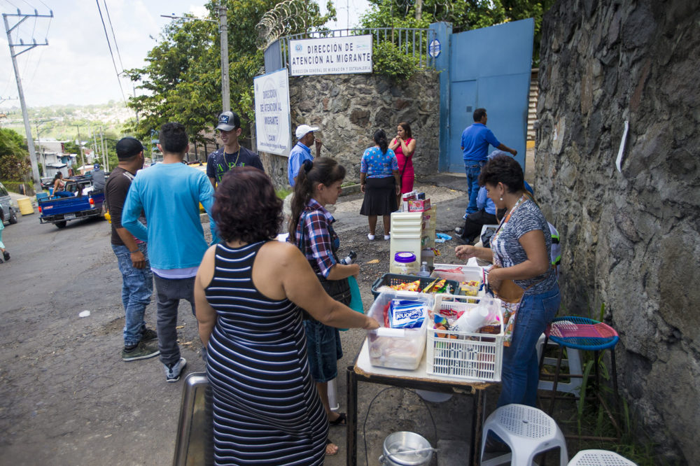 Shortly after being teleased, deportees purchase snacks and other various items from a woman set up outside of the Centro de Atención integral a Migrante (Comprehensive Migrant Care Center) in San Salvador. Photo by Jesse Costa for WBUR