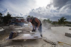 Jose Contreras saws a concrete block in half as he rebuilds his house in Barrio-Bravos de Boston, San Juan, which was completely destroyed by Hurricane Maria a year ago . Photo by Jesse Costa for WBUR