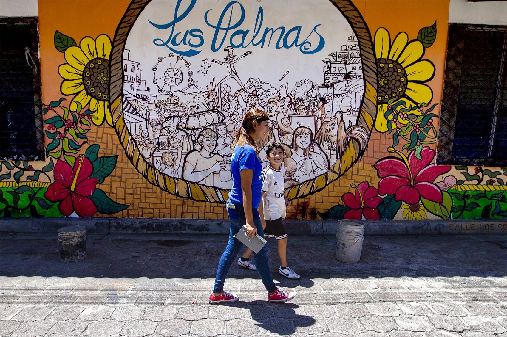 A Glasswing International staff member walks through town with a young boy who lives in Las Palmas. Photo by Jesse Costa for WBUR