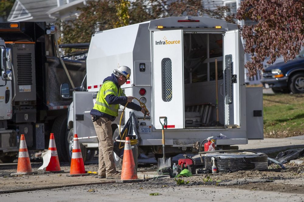 A utility worker hands a hose to another worker repairing gas lines underground that were damaged by a gas explosion on Salem Street in Lawrence. Photo by Jesse Costa for WBUR