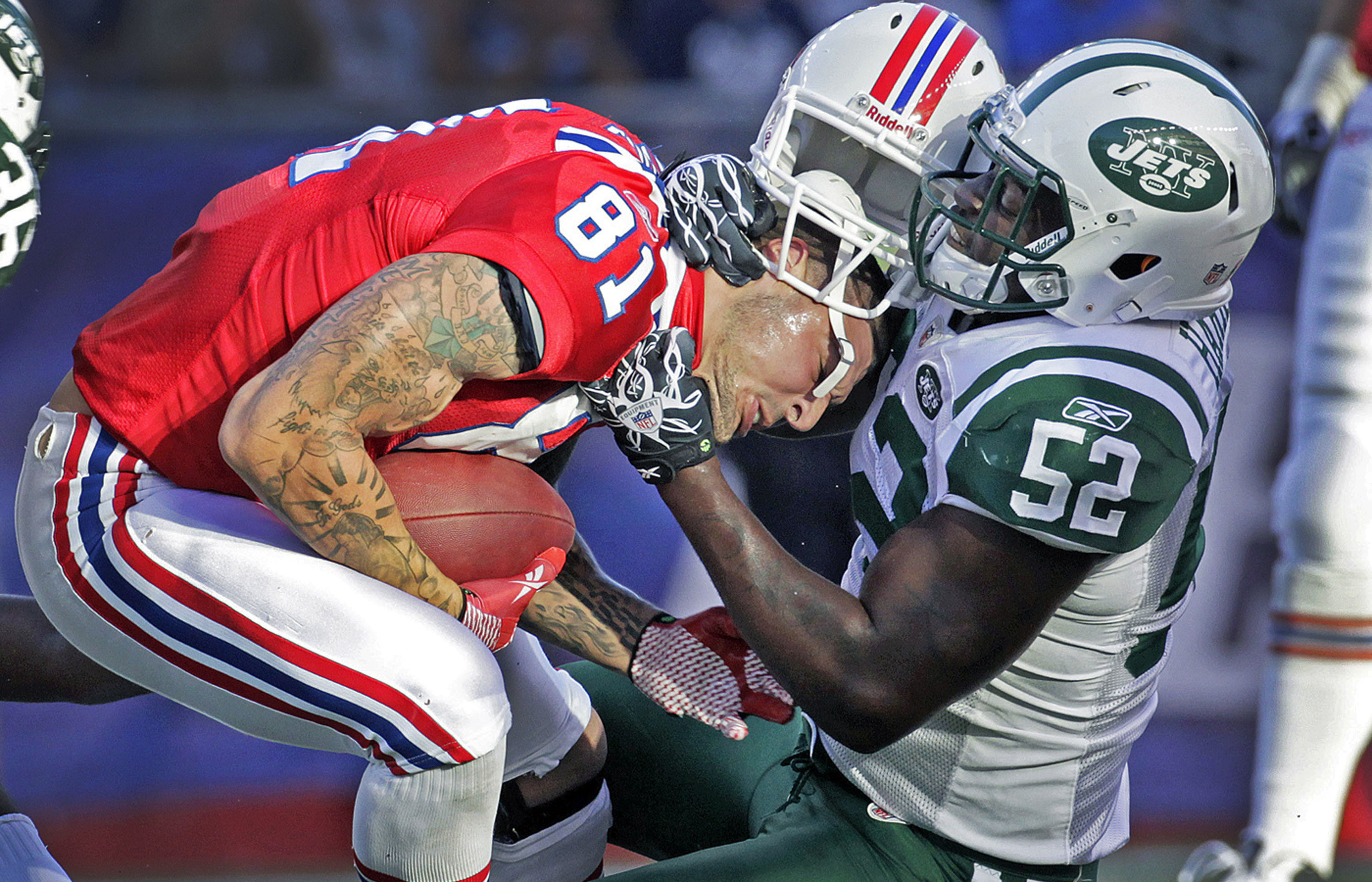 Patriots tight end Aaron Hernandez (left) is taken down by the Jets David Harris after a first quarter catch, and he loses his helmet in the process.  The New England Patriots hosted the New York Jets in a regular season NFL game at Gillette Stadium. Photo by Jim Davis for the Boston Globe. Courtesy of The Boston Globe