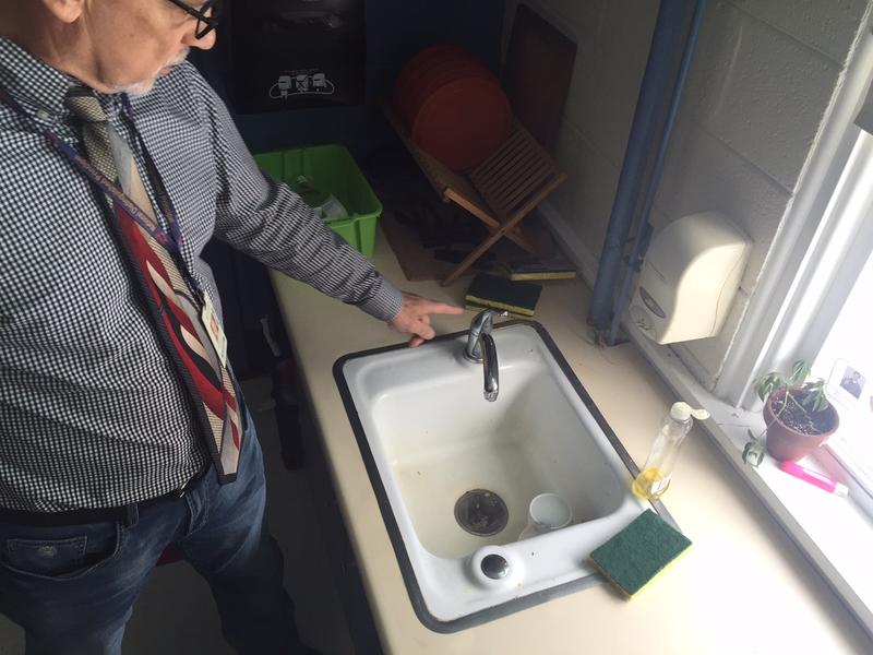 Andy Paciulli, who was Academy School principal when this photo was taken in February, points to one of the Brattleboro school's fixtures that was replaced after state tests discovered lead was leaching into the water. Photo by Howard Weiss-Tisman for VPR