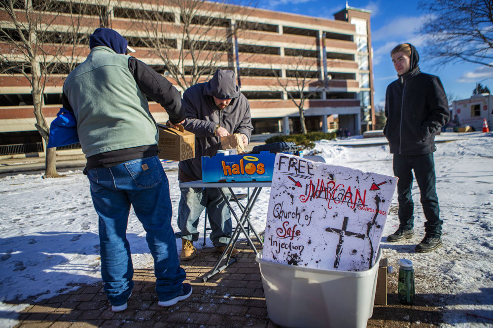 On a frigid 17º F afternoon in Pickering Square in Bangor, ME, two men stop by a folding table set up by The Church of Safe Injection for some coffee. Photo by Jesse Costa for WBUR