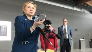 Gov. Janet Mills holds up a pound of carbon at a press conference at the Portland Jetport on Thursday. Photo by Fred Bever for Maine Public