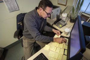 Army veteran Chris Riga rearranges sticky notes on his desk which he uses to organize and to assist him in remembering tasks he has to do throughout the day at his job as patient experience coordinator at the Northampton VA Medical Center in Leeds, MA. Photo by Jesse Costa for WBUR