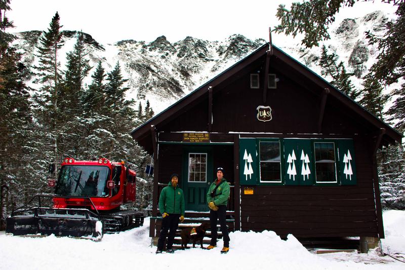 Avalanche Dog Lilly between Snow Rangers Helon Hoffer (left) and Frank Carus at the Snow Ranger cabin. Photo by Sean Hurley for NHPR