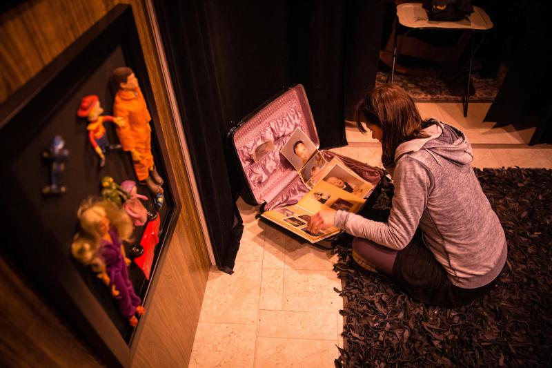 A visitor examines personal artifacts in the interactive exhibit "Memory in a Void," filled with Joe Dulude II's childhood memories. Photo credit of Matthew Cavanaugh