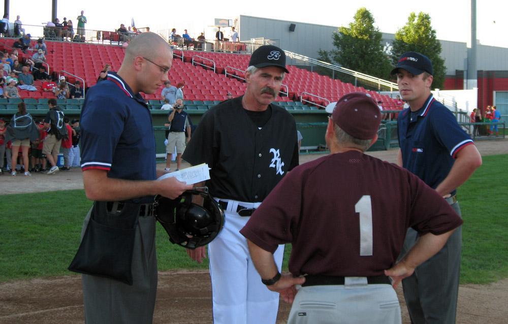 Bill Buckner, in black, speaks with umpires and the opposing manager before a 2011 Brockton Rox game. Photo by Anthony Brooks for WBUR