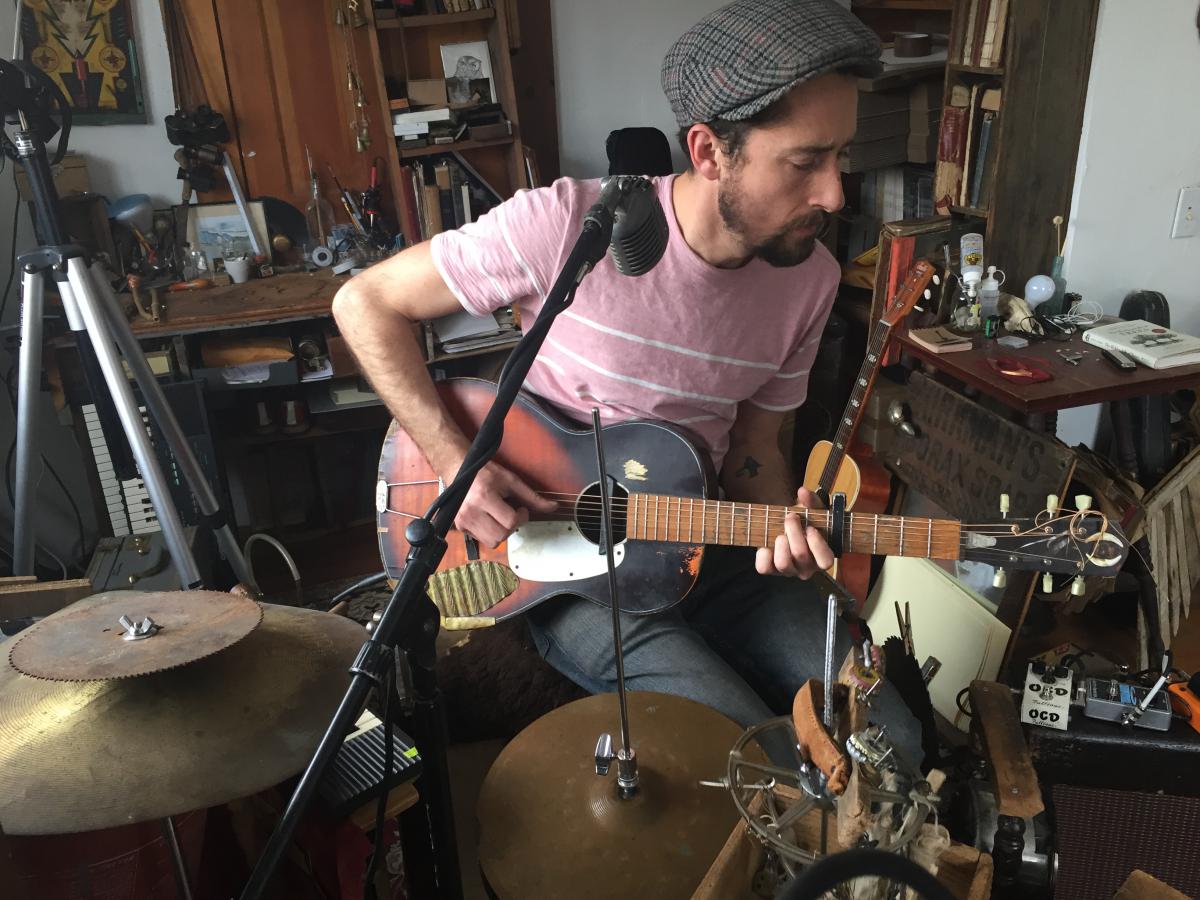 Matt Lorenz sits at a large contraption of homemade and traditional instruments. Photo by Karen Brown for NEPR