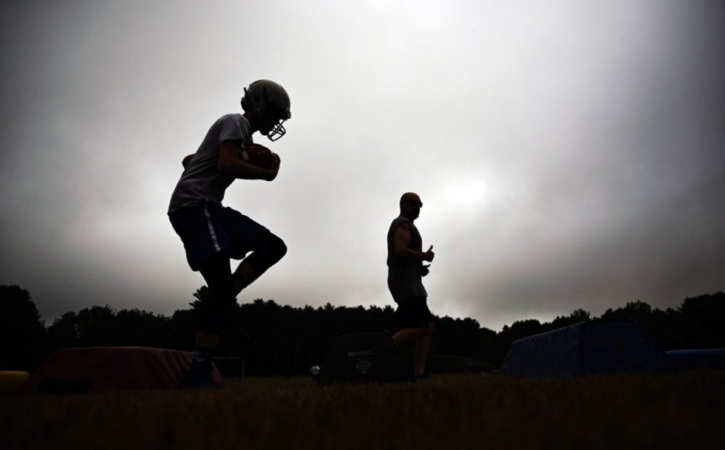 Assistant coach Jon Gallant, in the background, watches as players run drills at Old Orchard Beach's first football practice of the season Monday morning. Shawn Patrick Ouellette_Staff Photographer