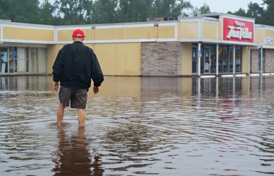 Bob Conyers crosses a flooded parking lot to check on his family-operated hardware store in Connecticut after Tropical Storm Henri made landfall in New England on Aug. 22, 2021.