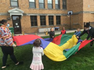 Preschool children playing outside, holding a colorful flag, at Mt. Carmel Early Education and Care Center in Chicopee, Massachusetts.