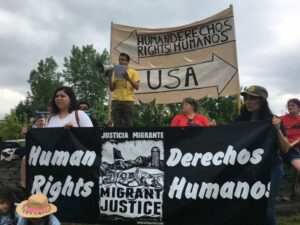 People hold up signs that say "Human Dignity/ Derechos Humanos" in support of migrant farmworkers in Vermont.