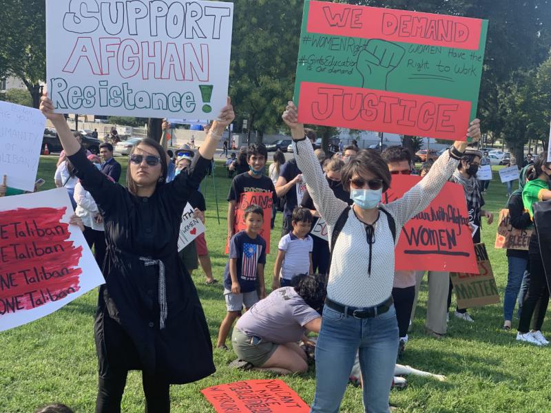 Two protesters hold protest signs