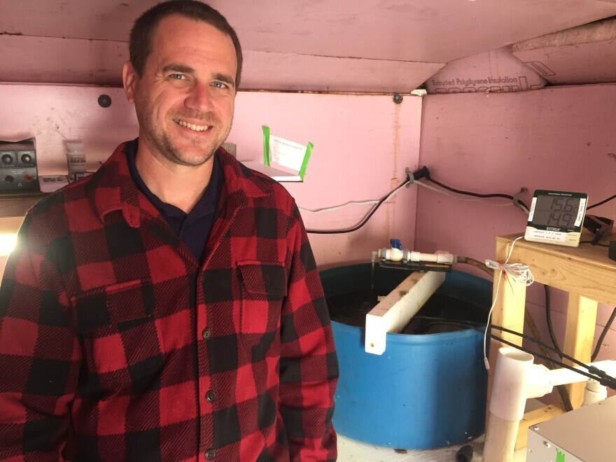 Brian Baumgaertel, director of the Massachusetts Alternative Septic System Test Center, stands near a blue wastewater tank used to test nitrogen-monitoring sensors like the one contained in a metal box, at right foreground. 