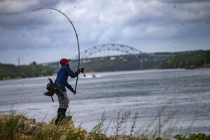 A fisherman casts his fishing line out into the Cape Cod Canal in Sandwich, Massachusetts.