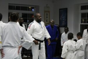 Sensei Papy Bongibo, center, and sensei Francis Bola, in blue, observe as students practice judo drills. Many students said Bongibo's standing in the community encouraged them to join the class.