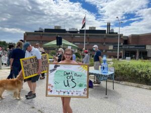 Berkeley Parenteau stands in front of the New Hampshire Department of Environmental Services during a rally against the development of a landfill near Forest Lake State Park.