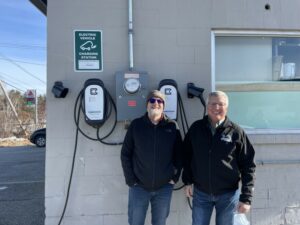 Stephen Foster, director of Facilities at Plymouth State University, and Bill Johnstone, business development executive at the New Hampshire Electric Co-op, stand in front of PSU's EV chargers. The school plans to get two new ones in the spring.