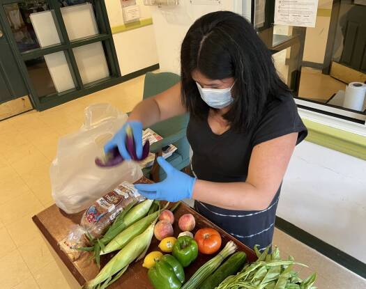 Lisette Le, executive director for VietAID, shows GBH's Sarah Betancourt the contents of a food bag the group distributes on Wednesdays.