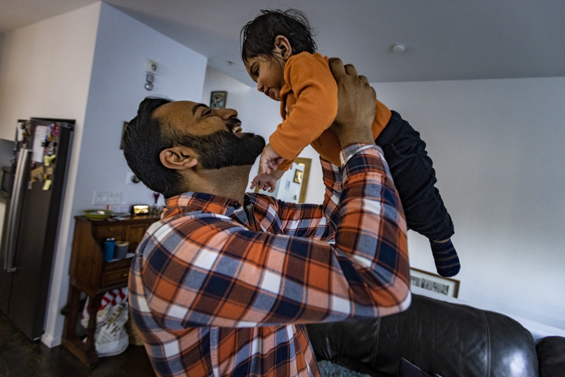 Raj Paik lifts his nine-month-old son Siraj after getting home from work. 