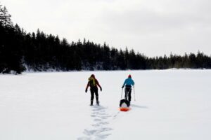 Julia Daly, left, and Rachel Hovel arrive at Midway Pond near Saddleback Mountain in Franklin County. Hovel pulls a sled full of gear they will use to take samples from the water.