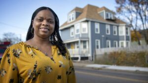 Cecilia Dixon stands on Harvard Street, Dorchester, by her new home.