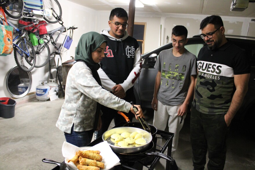 Zainab Manahe fries sambousas and other Ramadan specialties in her family's garage in Gorham, while her husband Mashan and two sons, Nasir (left) and Omar look on. Nasir said for him, the smell of sambousas is synonymous with Ramadan.