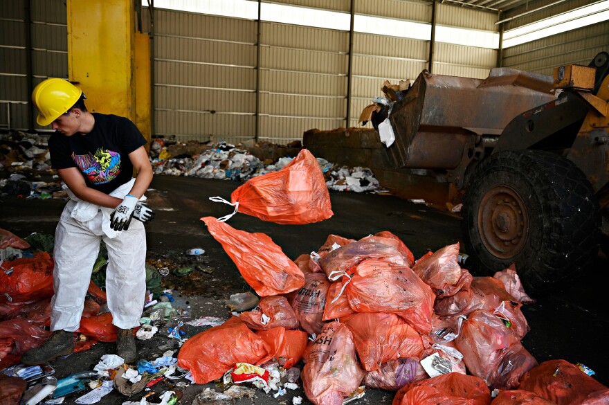 Cody Talento, who works for the city of Meriden, separates bags of trash from bags of food scraps at HQ Dumpsters and Recycling in Southington. The food waste will be taken to an anaerobic digester to be turned into electrical energy and compost. About 1,000 households in the town of Meriden are participating in a municipal food recycling pilot program. Experts and advocates say that separating out food waste will save money and help protect the environment.