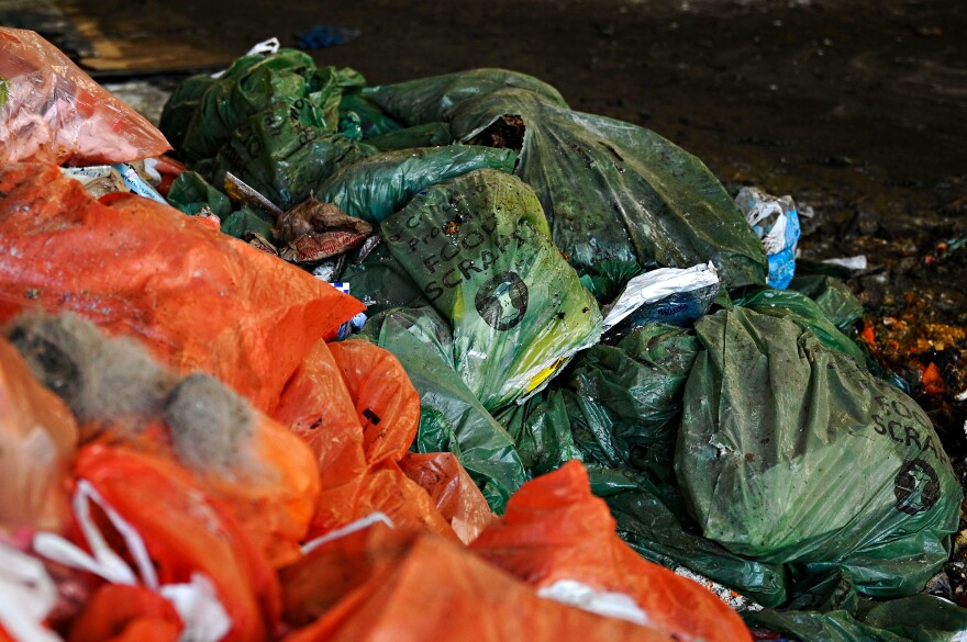 Green bags full of food scraps sit next to orange bags full of trash after being dropped off at HQ Dumpsters and Recycling in Southington. The load of waste materials is a part of a pilot municipal food waste recycling program in the town of Meriden, where about 1,000 households are part of a pilot to separate their old food from their trash to be transferred to an anaerobic digester and turned into electrical power and compost.