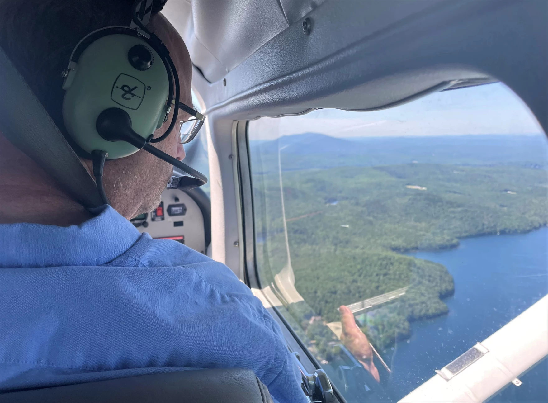 Forester Kyle Lombard looks out the window of a small airplane, searching for damage in the New Hampshire forest below.