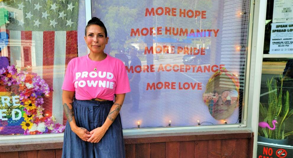 Miriam Kovacs stands in front of her Franklin, N.H. catering business, wearing a pink T-shirt that reads "PROUD TOWNIE." Kovacs has been a target of online harassment by white supremacists since she made a point of protesting their presence in New England.