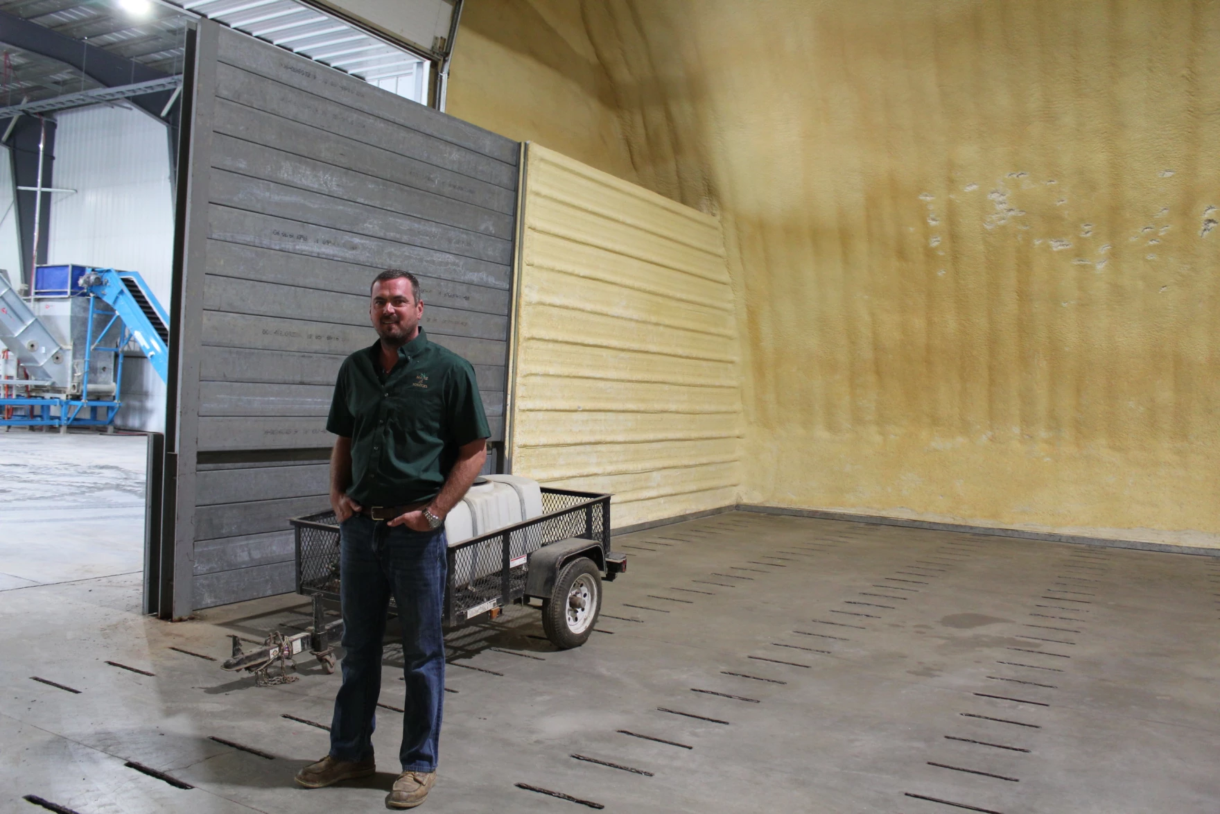 Farmer Robbie Irving, wearing a forest green button-down shirt with jeans, stands inside a packing facility created for the Caribou Russet, a variety of potato initially created on the UMaine research farm nearby.