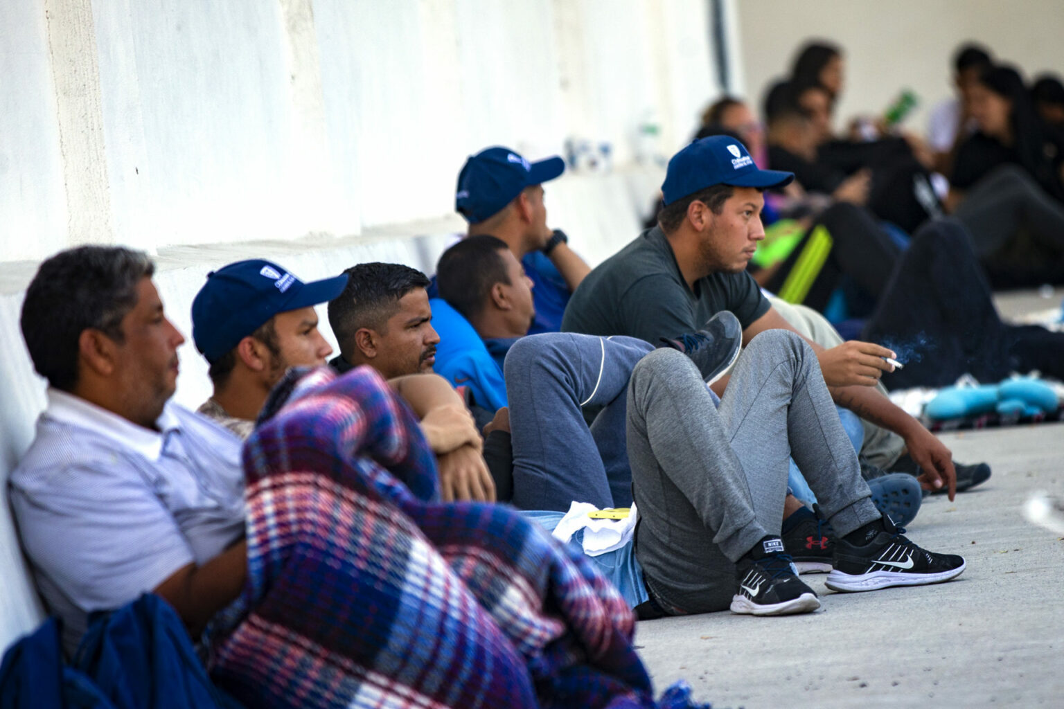 At least half a dozen men -- among the hundreds of Venezuelan immigrants waiting at the Ciudad Juarez office  of Consejo Estatal de Población -- sit against a wall as they wait. They're unable to cross the border into the U.S.