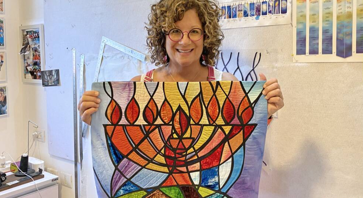 Jeanette Kuvin Oren in her studio with her original artwork for the Hanukkah stamp.