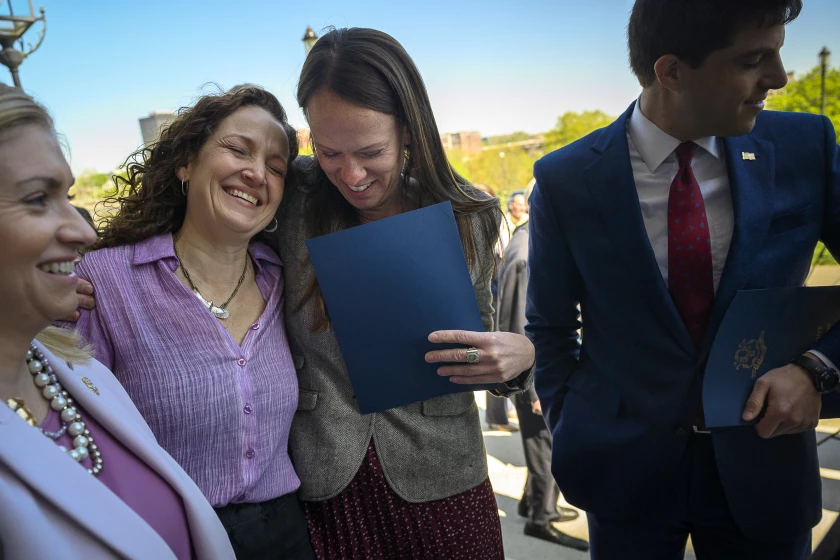 With Connecticut State Representative Matthew S. Blumenthal (right), Ct. State Reps. Jillian Gilchrest (second from right) hugs Aimee Berger-Girvalo after a bill signing ceremony that extended legal protections to out-of-state health-care providers and abortion patients.