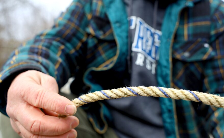 A closeup of a hand of Rob Martin, a fisherman and gear specialist who works for NOAA Fisheries, as he points out recovered rope intertwined with purple thread. Purple is the Maine state color, and has been found on at least seven humpback and minke whales within a three-year period. 