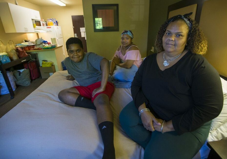 Lisbeth Sandoval, (far right), her daughter, Sheylibeth, and her son, Stephen, inside a hotel room in Lowell. Photo by Jesse Costa for WBUR